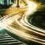 Lichtspuren von Fahrzeugen kreuzen sich bei Nacht auf einer Straßenkreuzung ohne erkennbare Ordnung