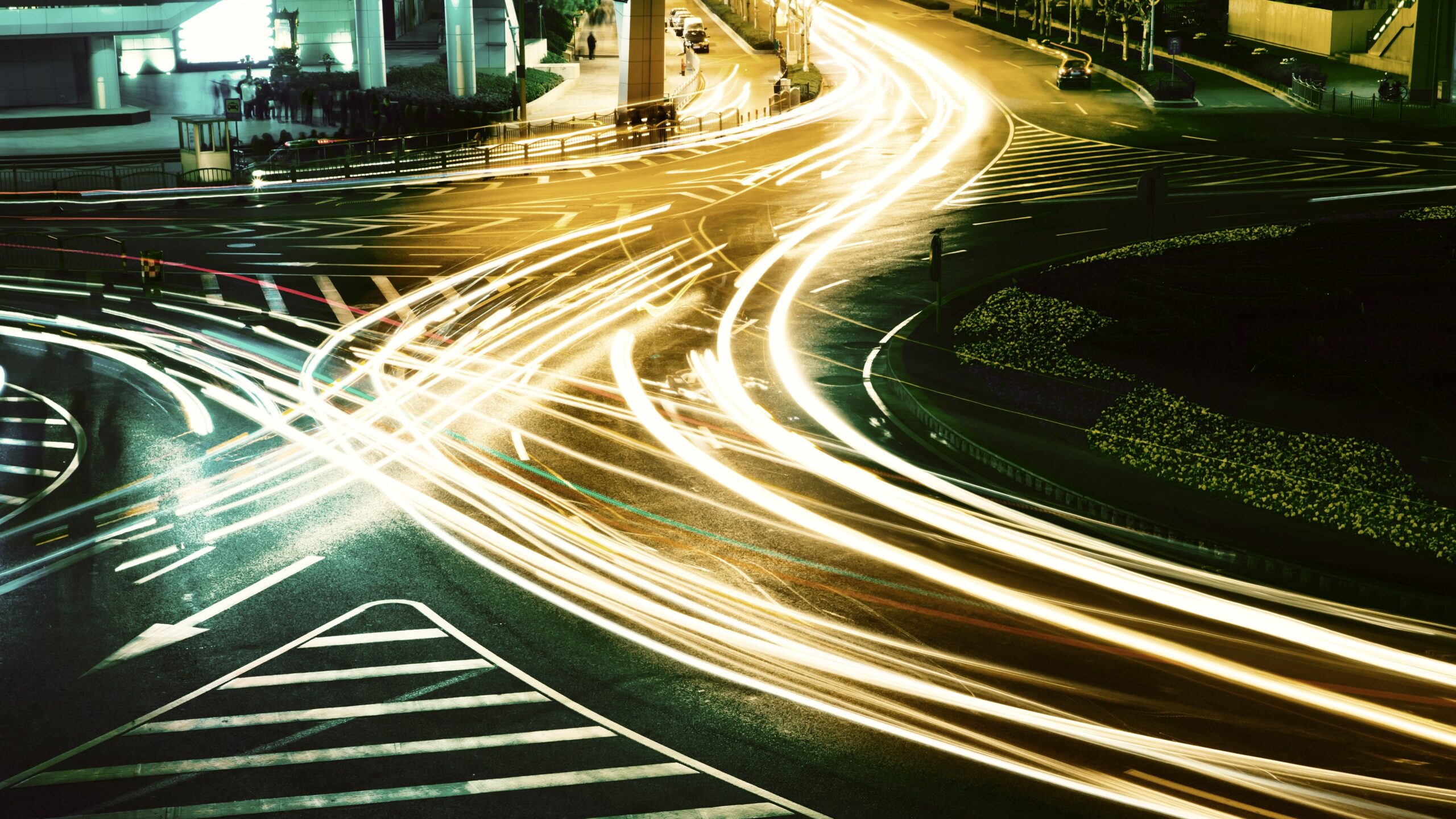 Lichtspuren von Fahrzeugen kreuzen sich bei Nacht auf einer Straßenkreuzung ohne erkennbare Ordnung